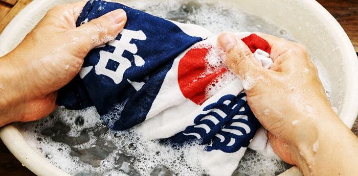 オリジナルのイラスト・柄・文字が名入れ印刷された手ぬぐいを手洗いで洗濯している画像