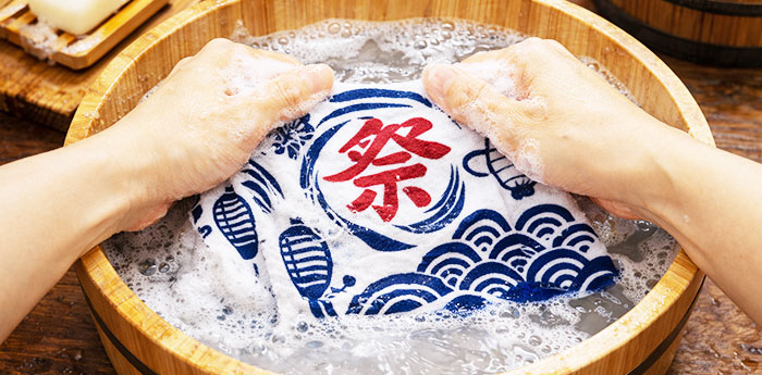 お祭り用の提灯のイラストと、祭という字が赤色で名入れ印刷された手ぬぐいを手洗いで洗濯している画像