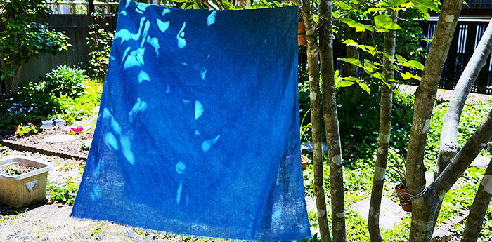 洗濯した後の藍色の手ぬぐいを、日陰の風通し良い場所で干している画像