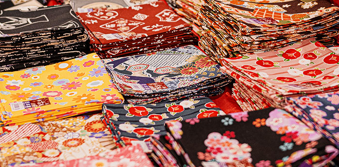 赤い風船のイラスト・赤い花柄・青色の魚・白色と藍色のひらがなの文字などがそれぞれに描かれている6枚の手ぬぐいが、折りたたんだ状態で並んでいる画像